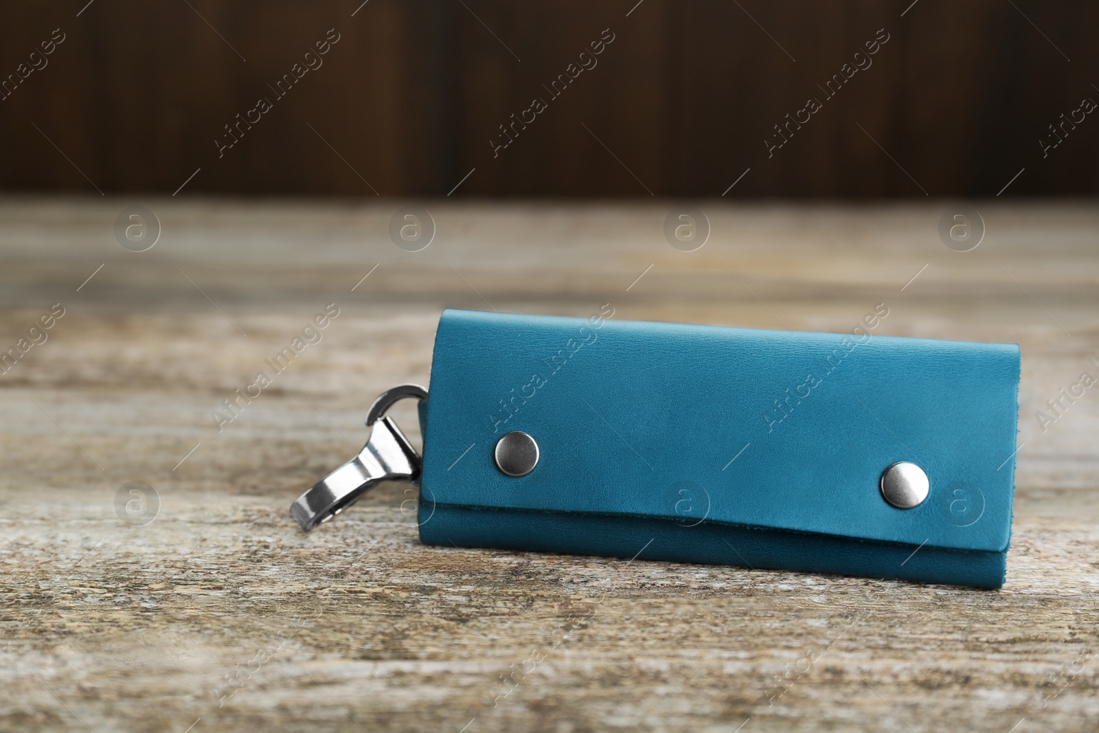 Photo of Stylish leather keys holder on old wooden table, closeup. Space for text