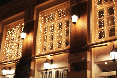 Blurred view of building with beautiful street lights at night. Bokeh effect