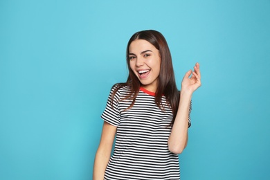 Portrait of young woman laughing on color background