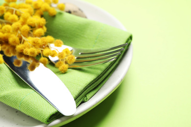 Photo of Festive Easter table setting with floral decor on green background, closeup
