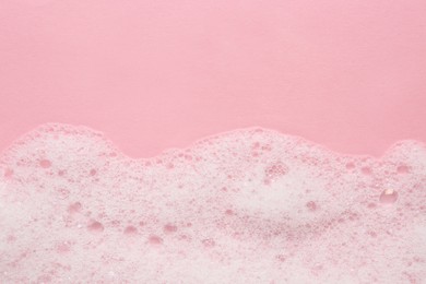 Photo of Fluffy bath foam on pink background, top view. Space for text