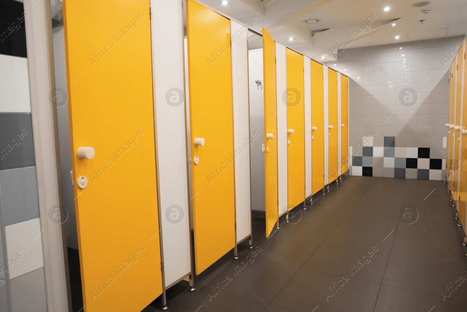 Photo of Public toilet interior with bright yellow stalls