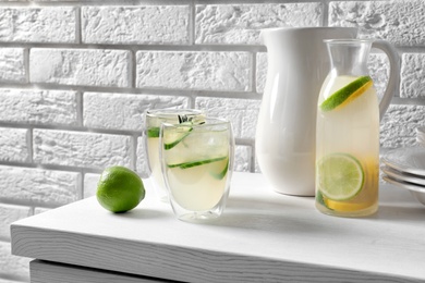 Photo of Glasses and bottle of fresh lemonade on table