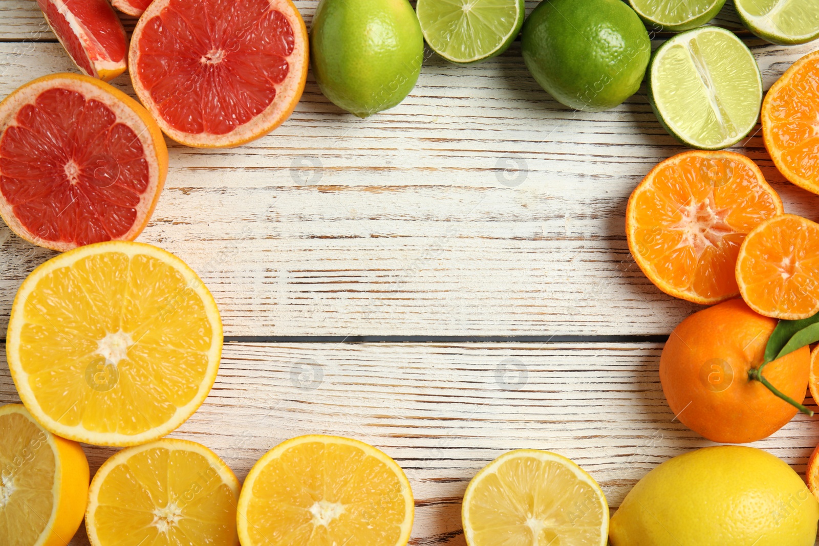 Photo of Frame made of different citrus fruits on wooden background, top view. Space for text