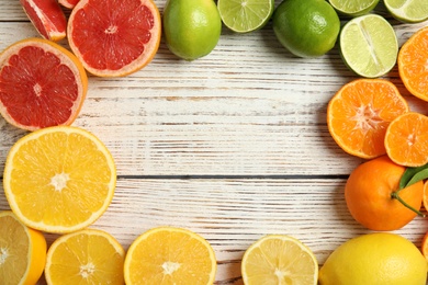 Frame made of different citrus fruits on wooden background, top view. Space for text