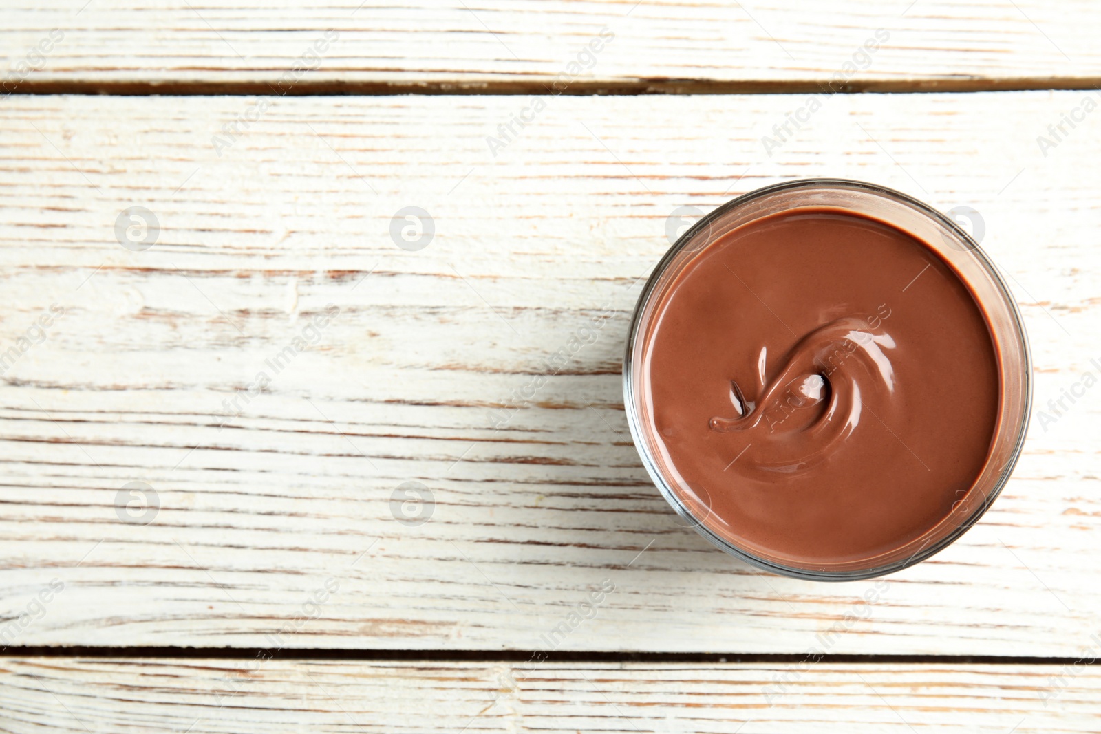 Photo of Glass with tasty chocolate cream on wooden background, top view. Space for text