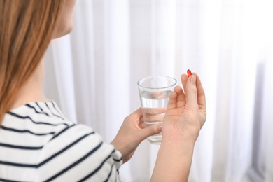 Photo of Young woman taking pill, closeup