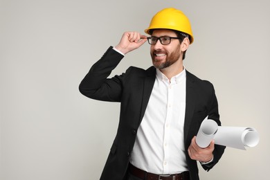 Architect in hard hat with drafts on gray background, space for text