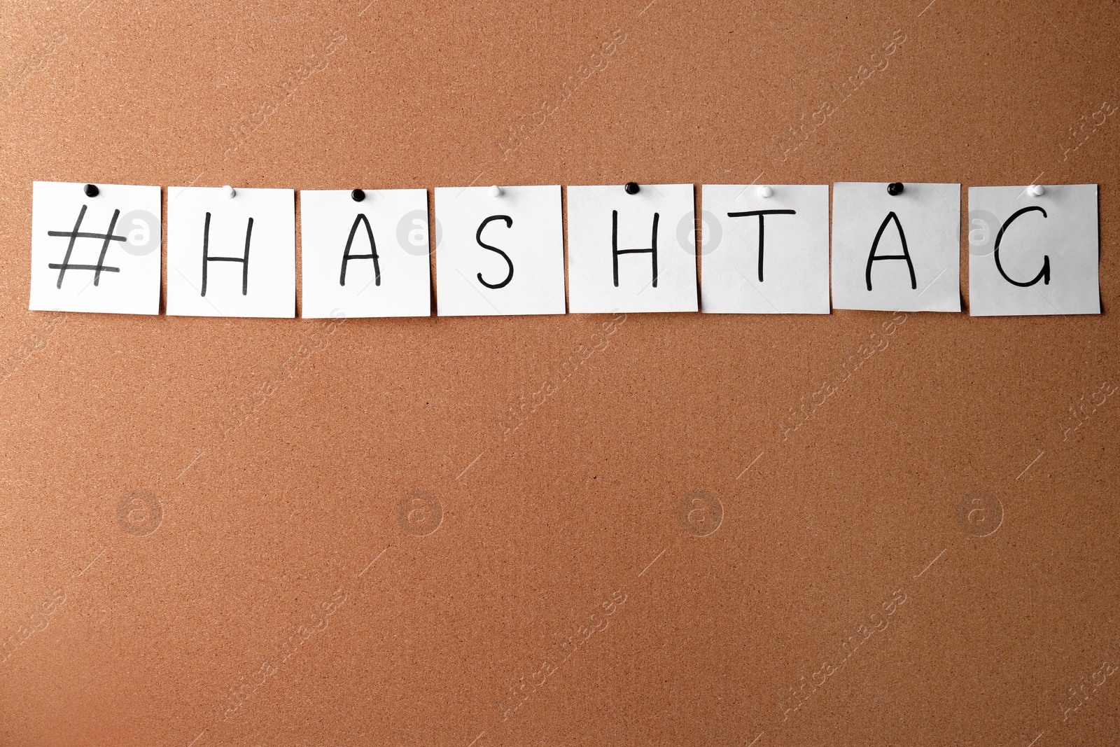 Photo of White note papers with word Hashtag and symbol pinned on corkboard. space for text