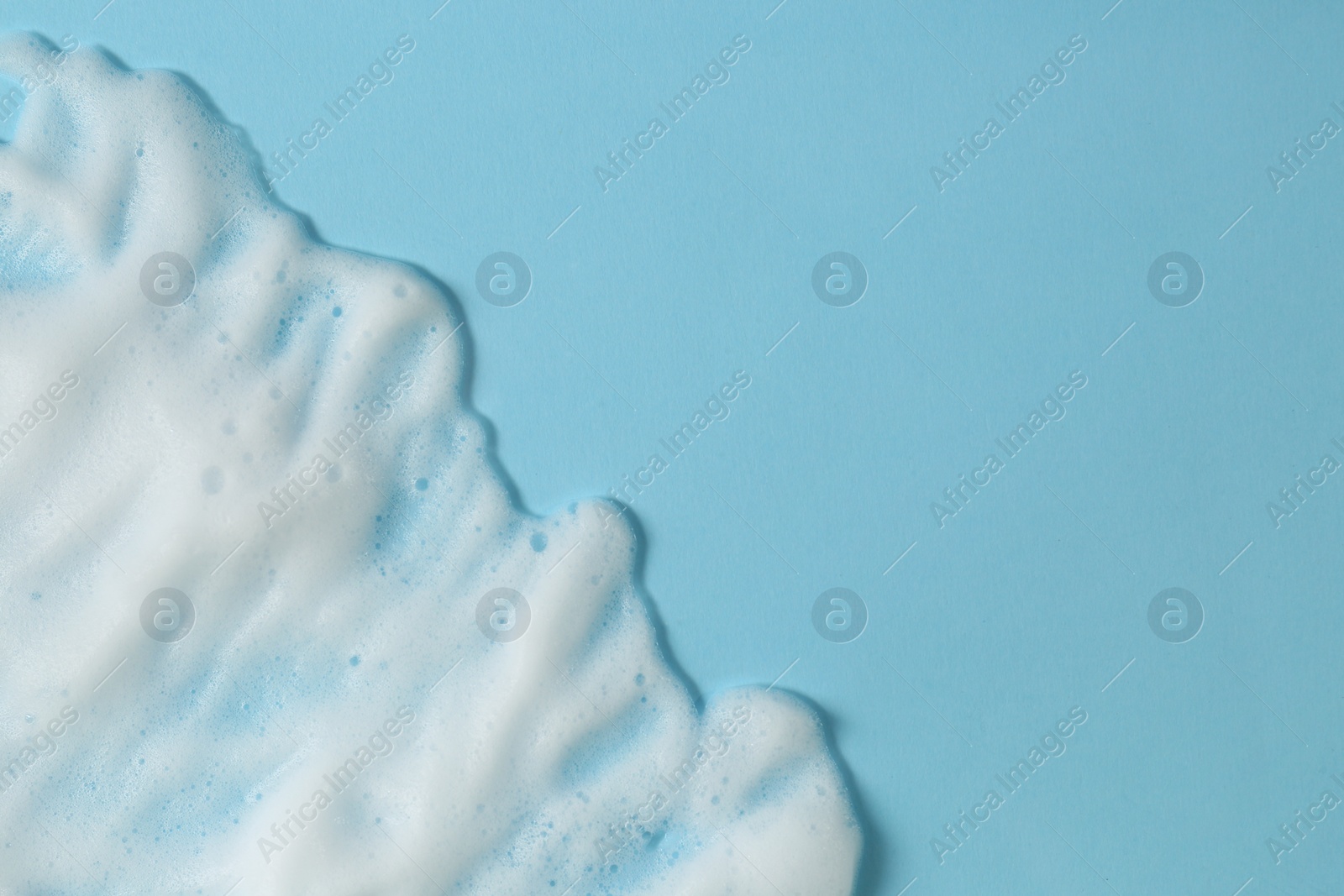 Photo of White washing foam on light blue background, top view with space for text. Face cleansing product