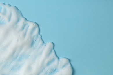 Photo of White washing foam on light blue background, top view with space for text. Face cleansing product