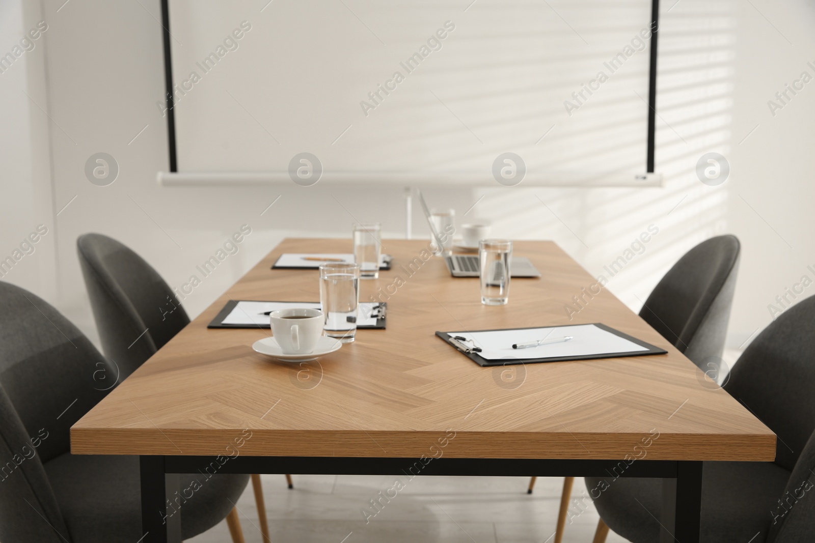 Photo of Conference room interior with glasses of water and clipboards on wooden table