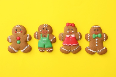 Photo of Christmas human shaped gingerbread cookies on yellow background, flat lay