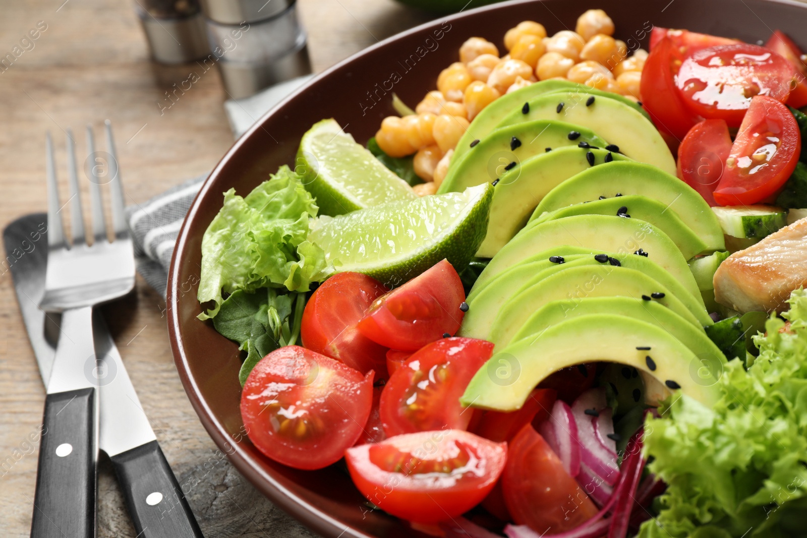 Photo of Delicious avocado salad with fried chicken on wooden table, closeup