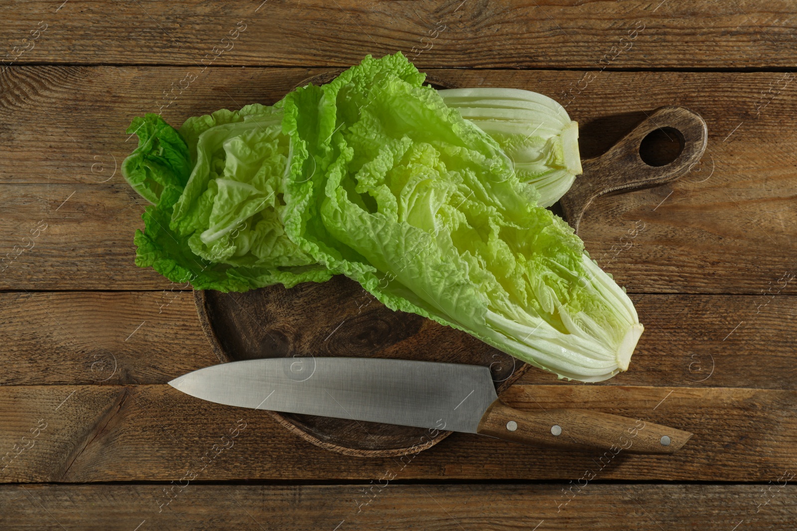 Photo of Halves of fresh ripe Chinese cabbage and knife on wooden table, flat lay