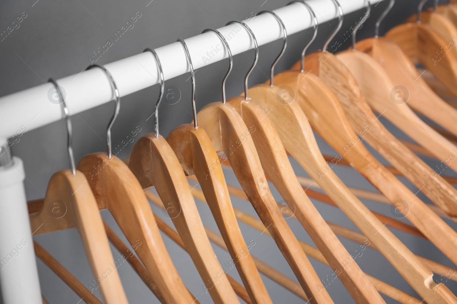 Photo of Clothes rail with wooden hangers on gray background