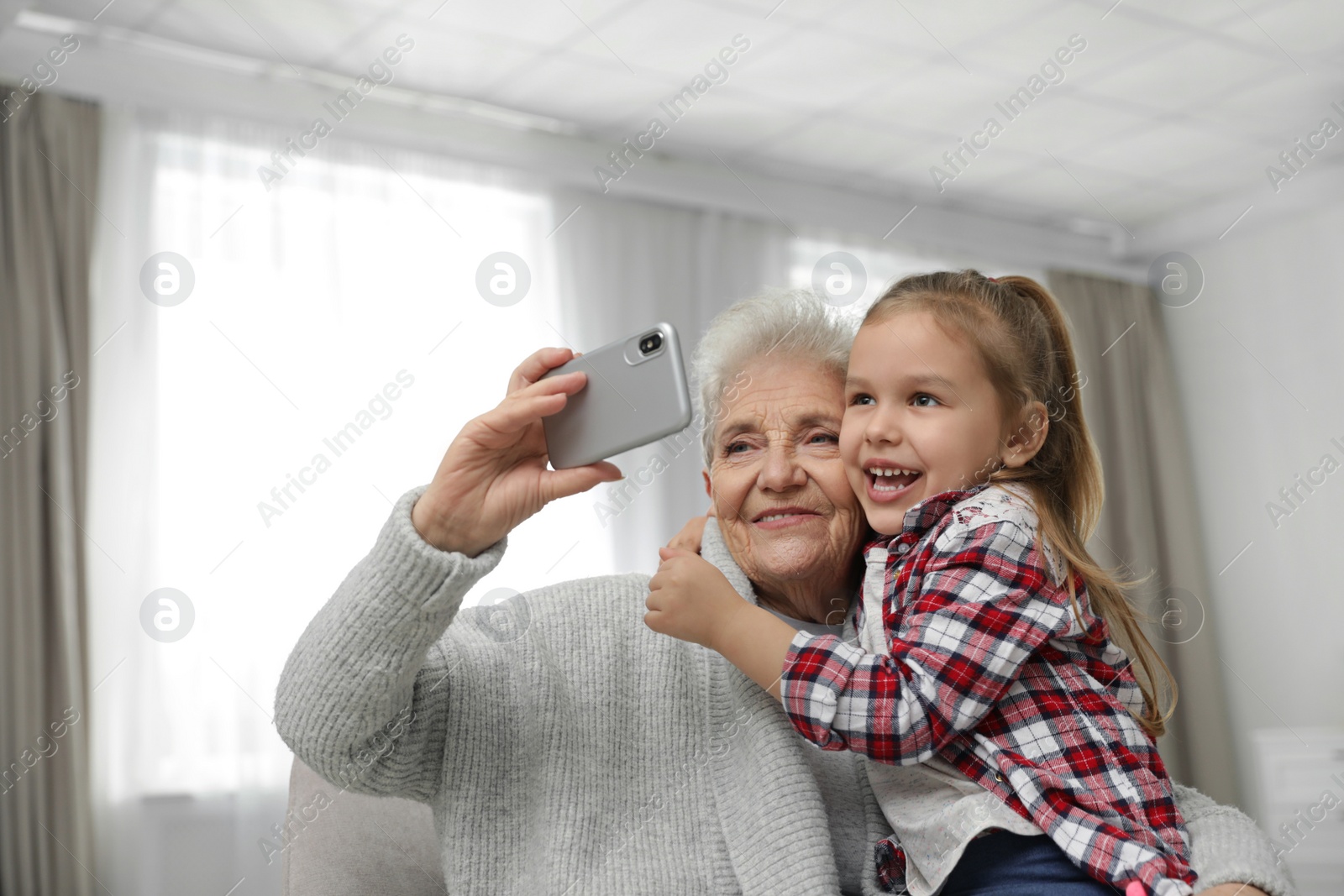 Photo of Cute girl and her grandmother taking selfie  at home