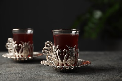 Photo of Glass of traditional Turkish tea in vintage holder on grey table