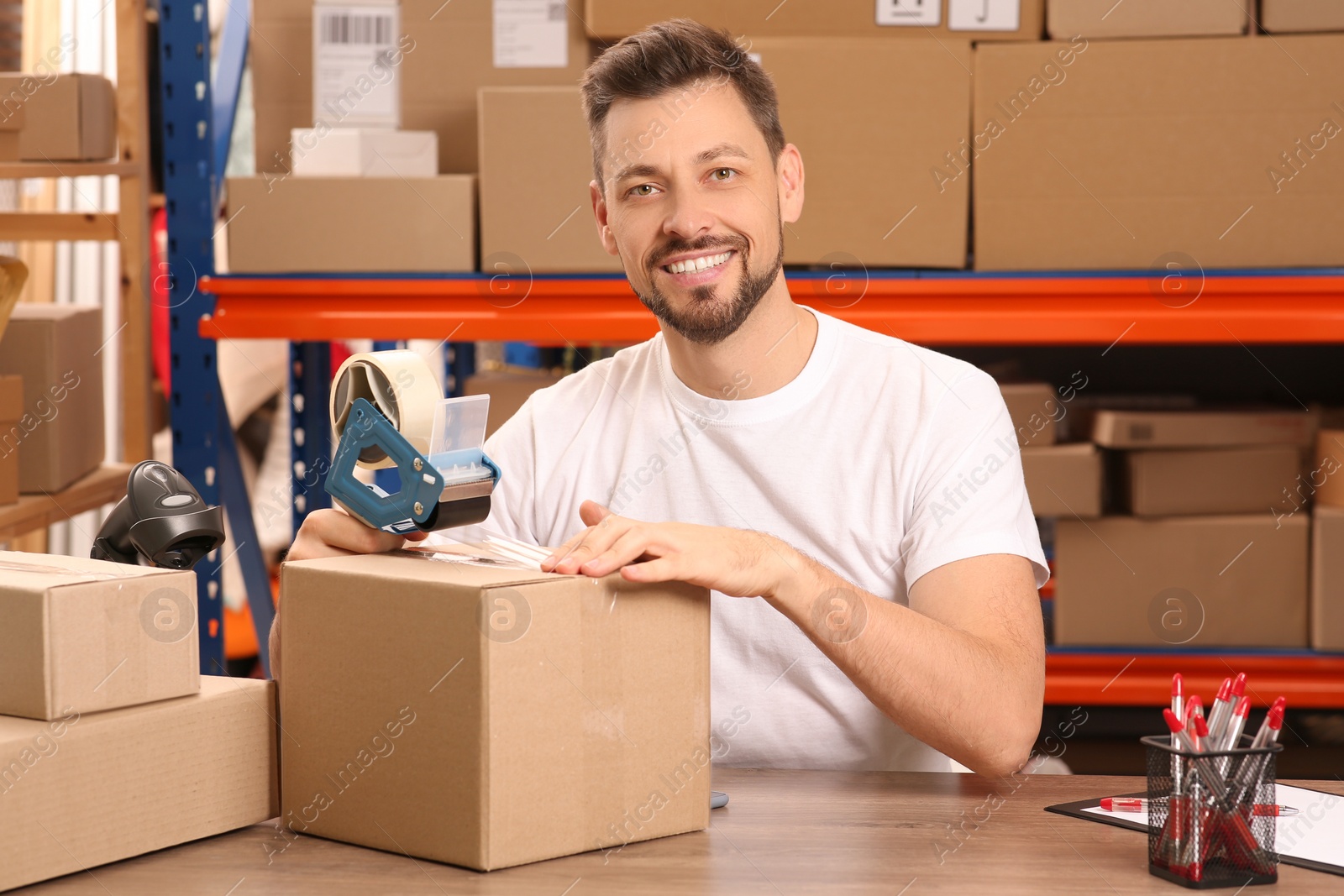 Photo of Post office worker packing parcel at counter indoors