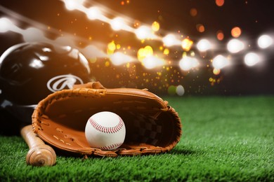 Image of Baseball bat, glove, helmet and ball on grass at stadium