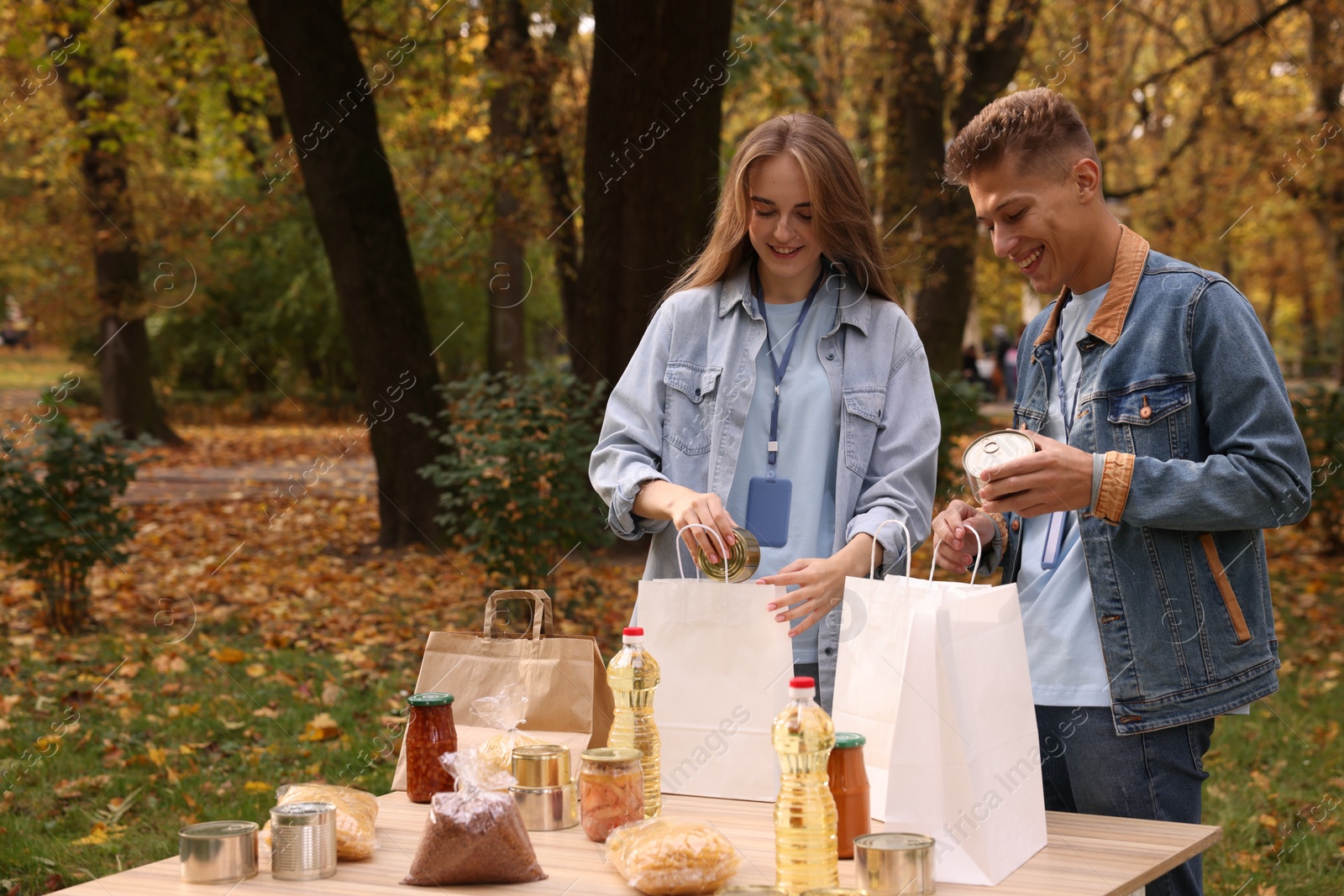 Photo of Volunteers packing food products at table in park