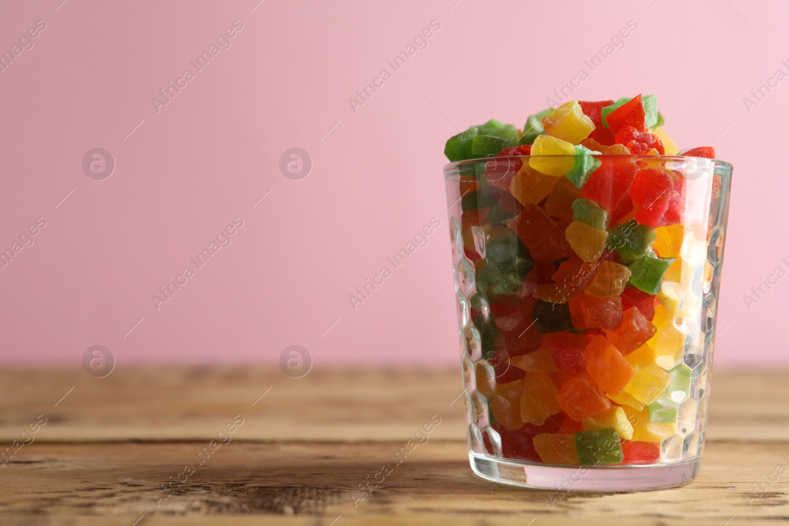 Photo of Delicious candies in glass on wooden table, closeup. Space for text