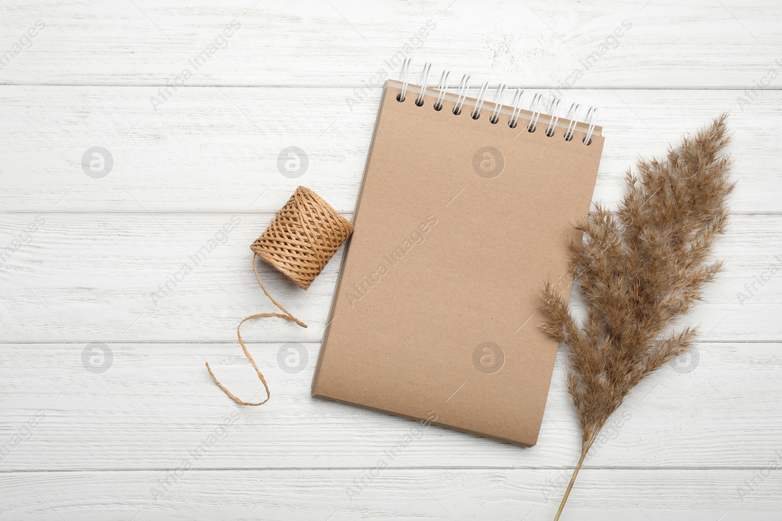 Photo of Stylish kraft notebook and decor elements on white wooden table, flat lay. Space for text