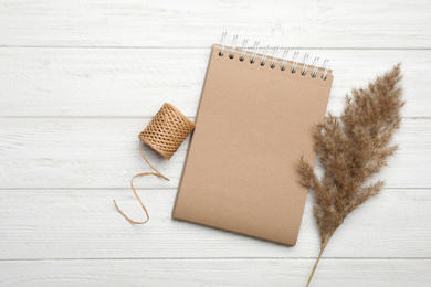 Photo of Stylish kraft notebook and decor elements on white wooden table, flat lay. Space for text
