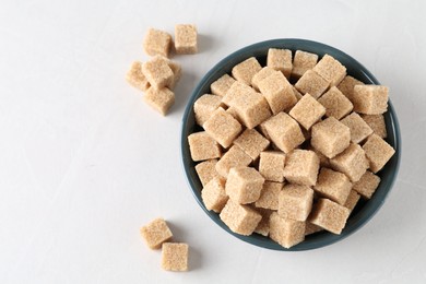 Photo of Brown sugar cubes on white table, flat lay. Space for text