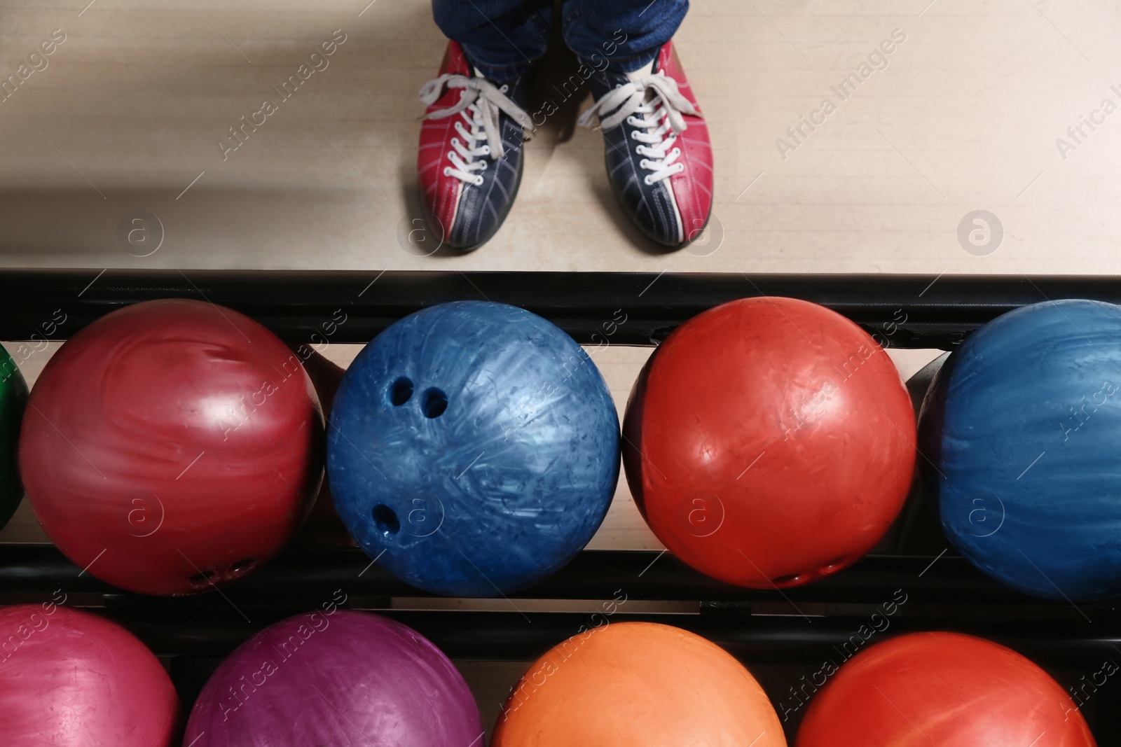 Photo of Person in bowling shoes near rack with balls, top view