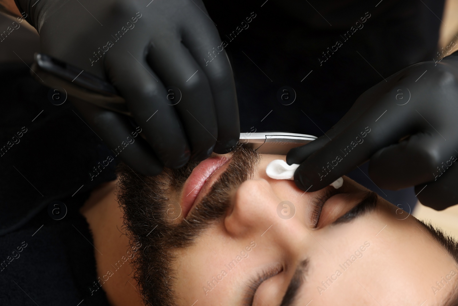 Photo of Professional hairdresser working with client in barbershop, closeup