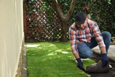 Photo of Young man laying grass sod on ground at backyard, space for text