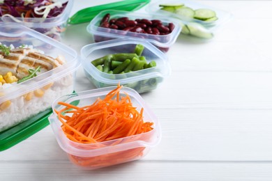 Set of plastic containers with fresh food on white wooden table, space for text