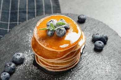 Tasty pancakes with berries and honey on slate plate