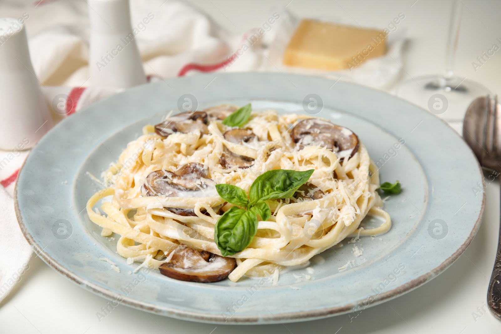 Photo of Delicious pasta with mushrooms and cheese on white table, closeup