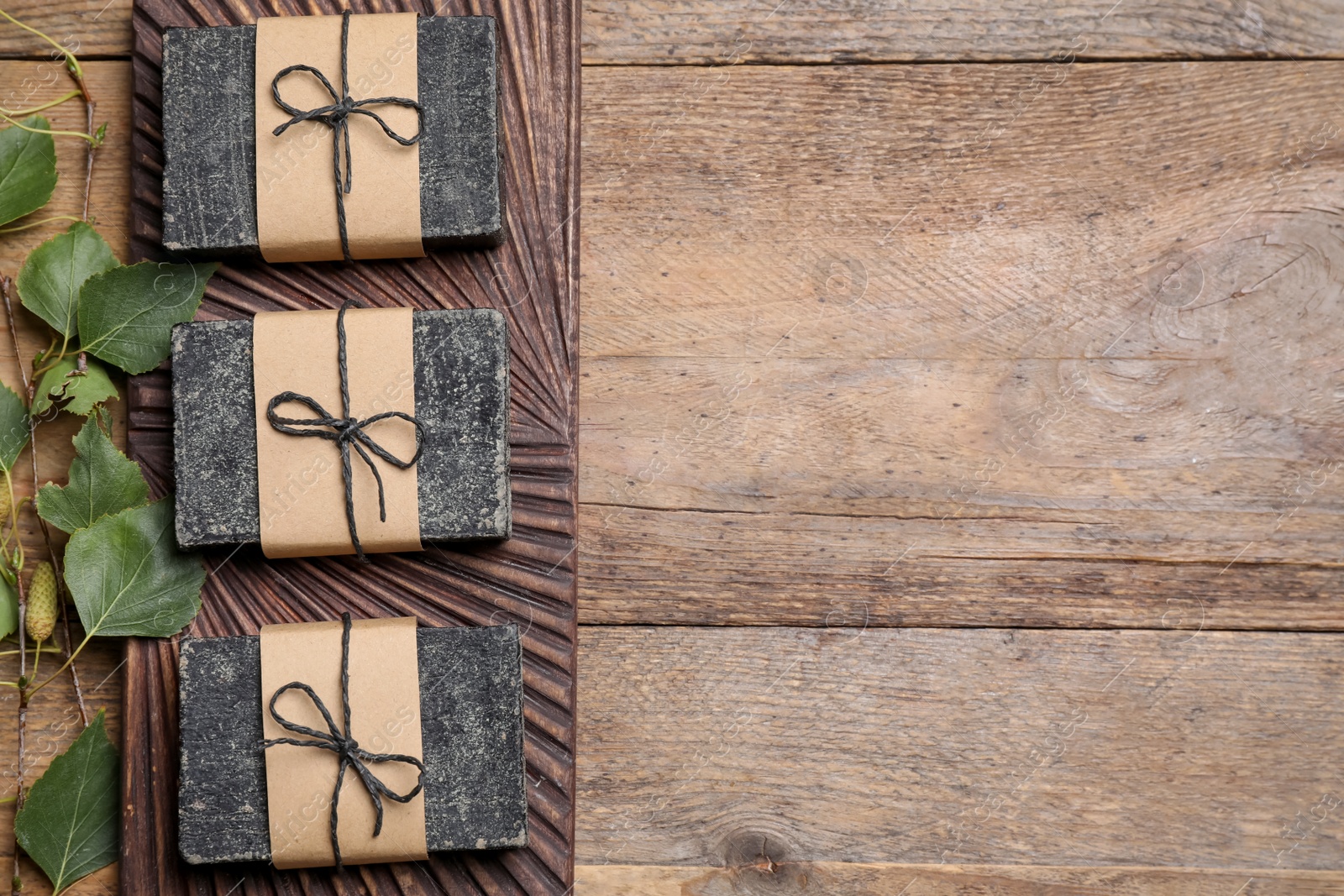 Photo of Natural tar soap on wooden table, flat lay. Space for text