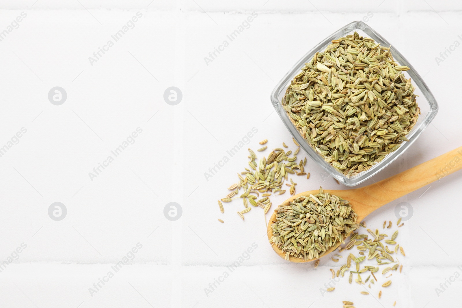Photo of Bowl and spoon with fennel seeds on white table, flat lay. Space for text