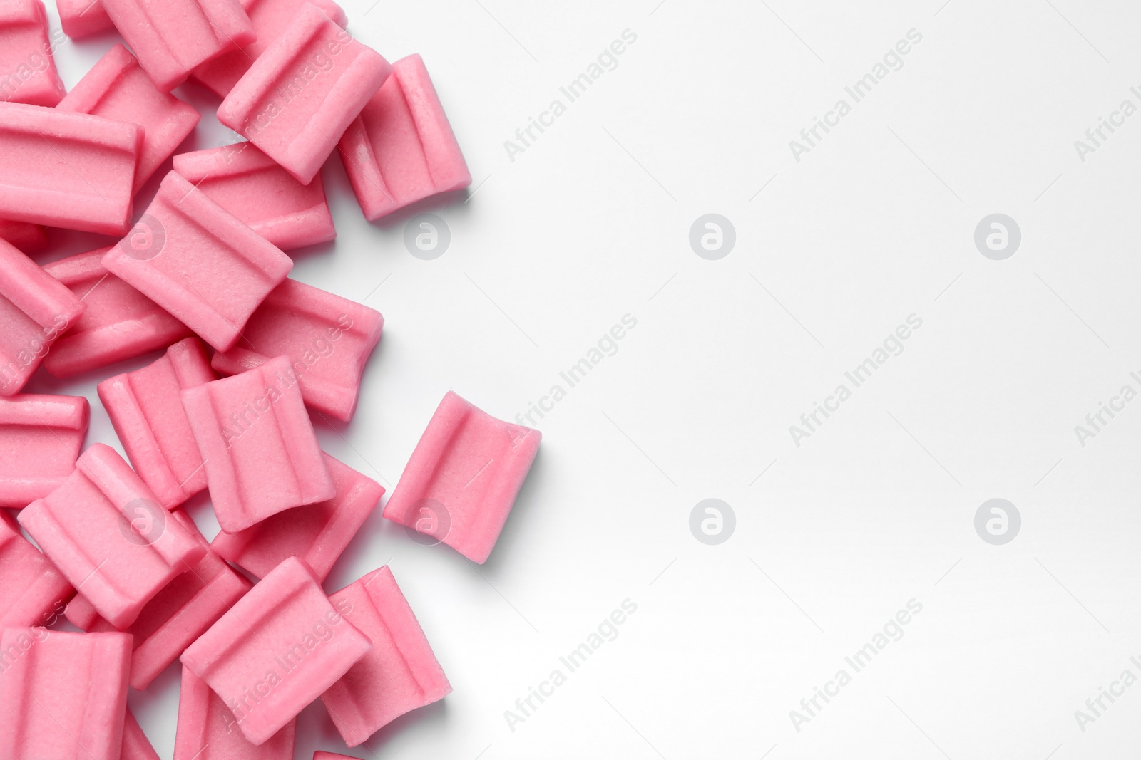 Photo of Tasty pink chewing gums on white background, flat lay. Space for text