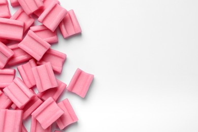 Photo of Tasty pink chewing gums on white background, flat lay. Space for text