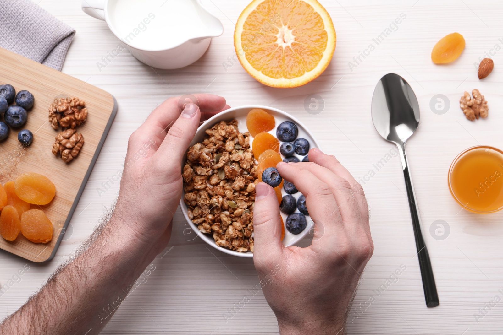 Photo of Man making granola at white wooden table, top view