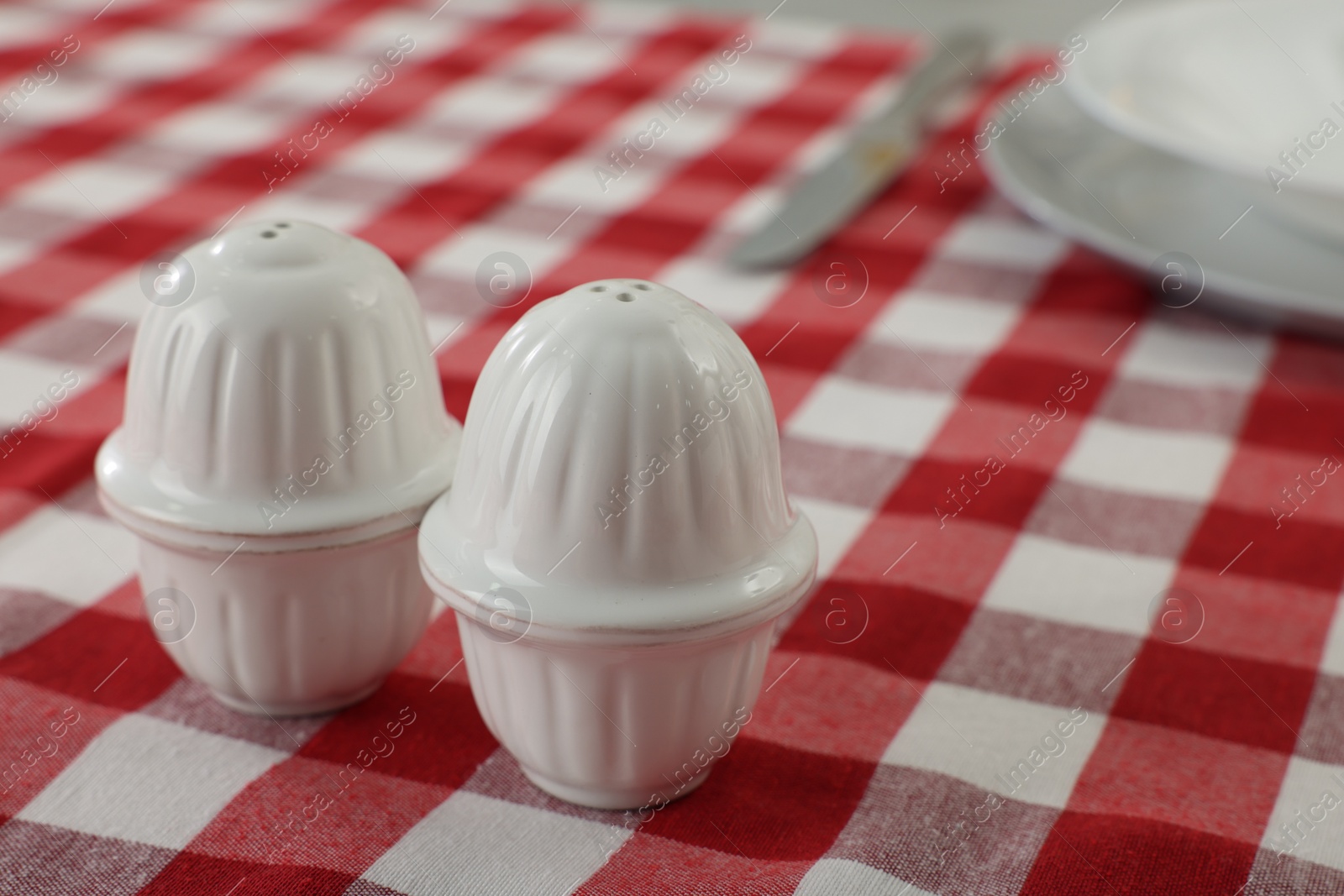 Photo of Ceramic salt and pepper shakers on kitchen table. Space for text