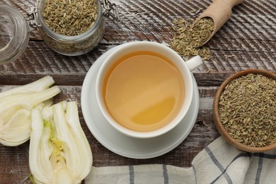 Photo of Aromatic fennel tea, seeds and fresh vegetable on wooden table, flat lay