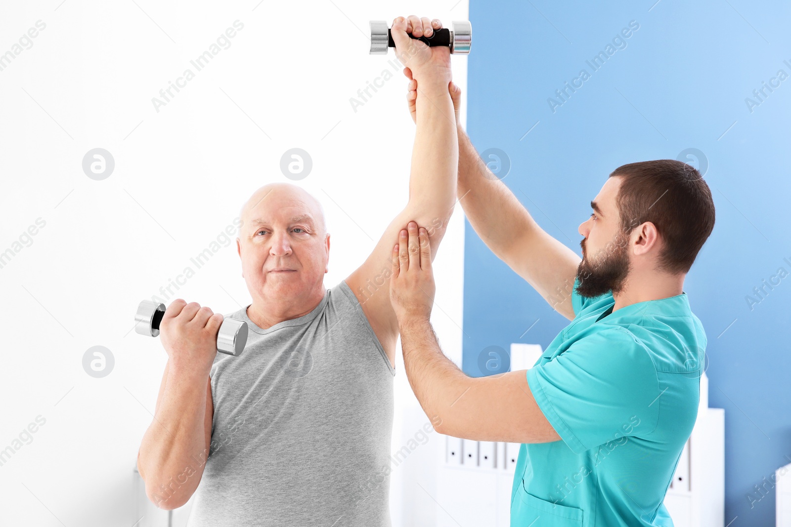 Photo of Young physiotherapist working with senior patient in clinic