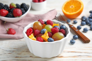 Fresh tasty fruit salad on white wooden table