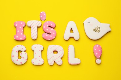Photo of Phrase IT IS A GIRL made of tasty cookies on yellow background, flat lay. Baby shower party