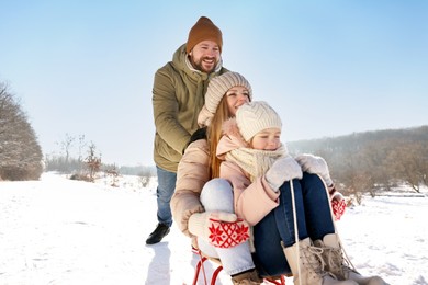 Photo of Happy family having fun with sledge outdoors on snowy day