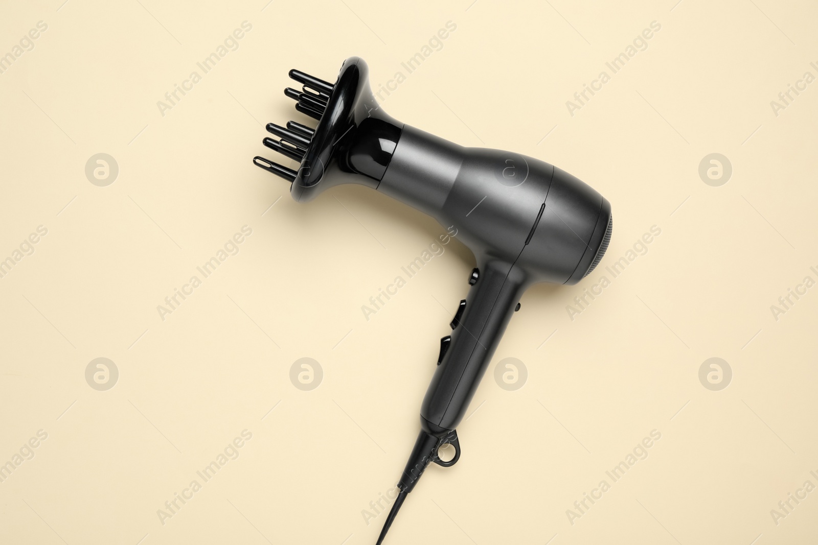 Photo of Hair dryer on beige background, top view. Professional hairdresser tool