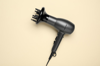 Hair dryer on beige background, top view. Professional hairdresser tool