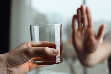 Photo of Man refusing to drink whiskey indoors, closeup. Alcohol addiction treatment