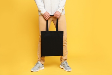 Young man with eco bag on yellow background, closeup